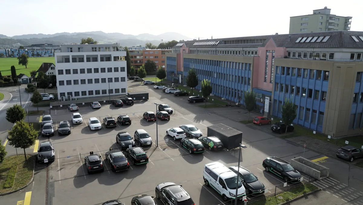 Man sieht einen Parkplatz und ein grosses Haus von oben.